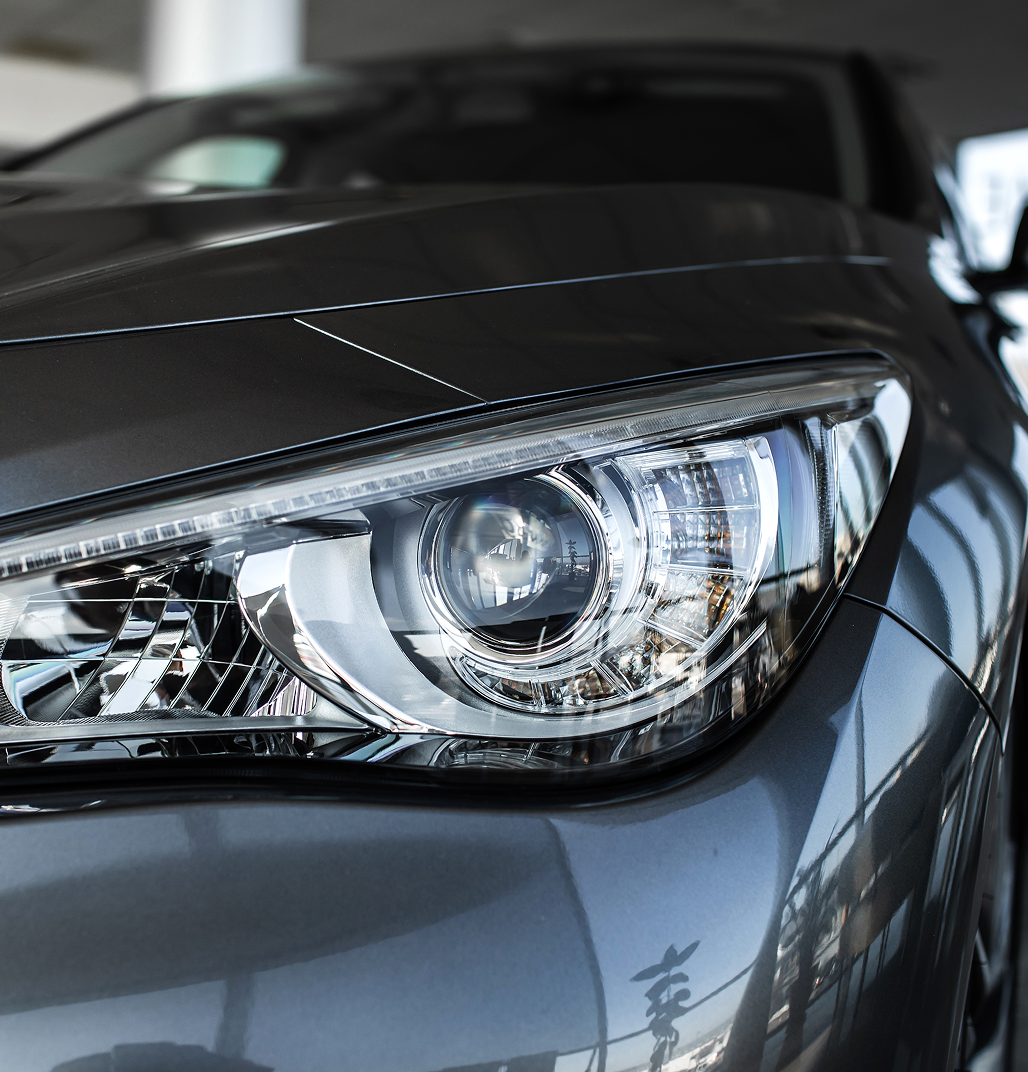 Close-up of a clean, glossy car headlight and hood